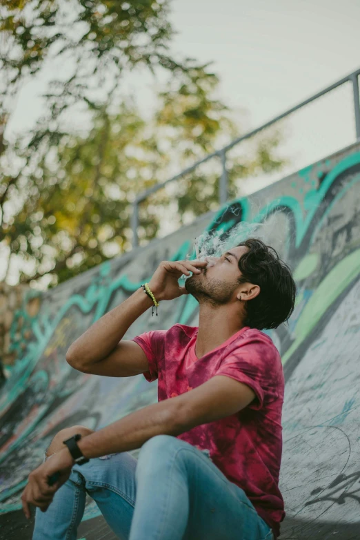 man sitting on a skateboard and drinking a water bottle