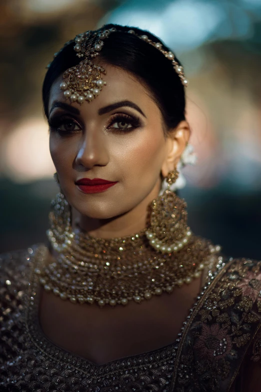 an attractive woman with dark makeup and gold jewelry