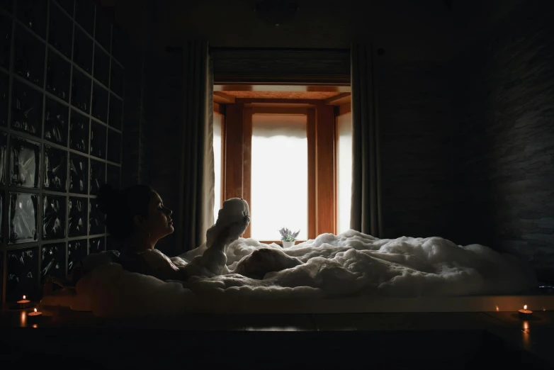 a woman lying in a bath tub with lots of foam on the floor