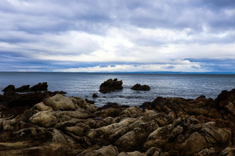 a rocky coastline with rocks under an overcast sky