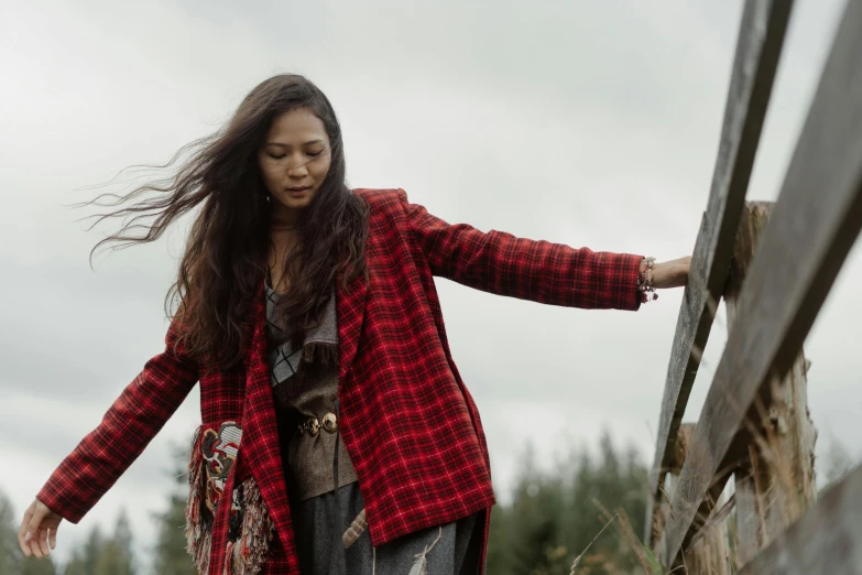 a woman standing next to a wooden fence