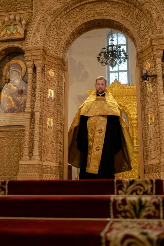 man wearing gold church robe in cathedral looking towards altar