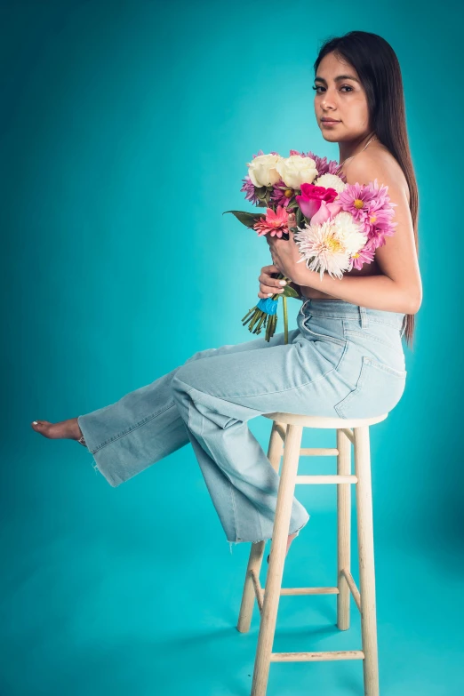 a woman with flowers on a stool posing for the camera