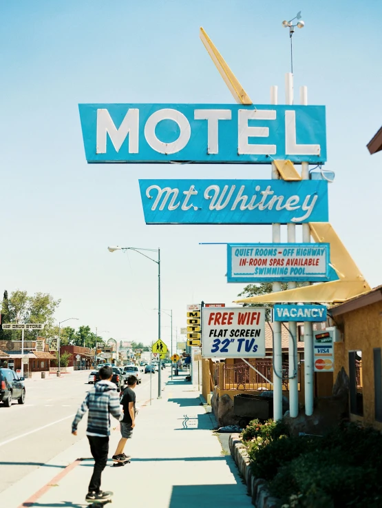 a blue motel sign hanging above a sidewalk