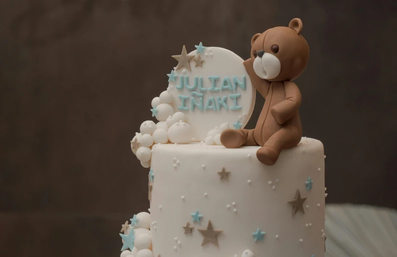 a teddy bear sitting on top of a tiered cake