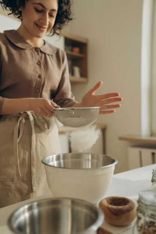 a woman is adding flour in a mixing bowl