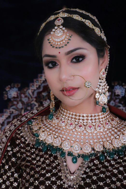 a young indian bride with black makeup and gold jewelry