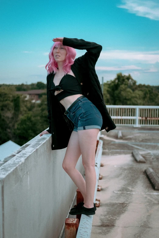 a woman with pink hair standing on top of a wall