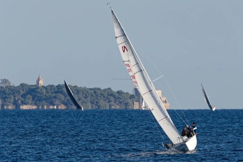 several sail boats sailing in the middle of a body of water