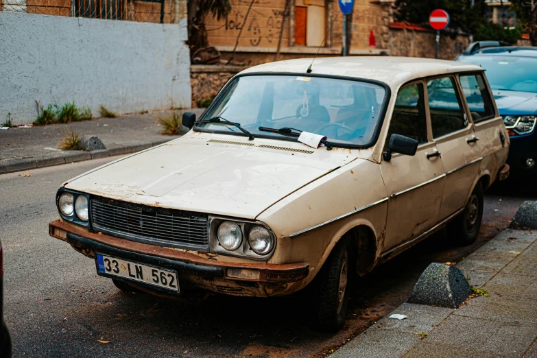 a dirty old car parked on the street