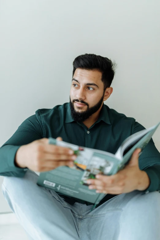 a man sitting on the ground and looking at a book