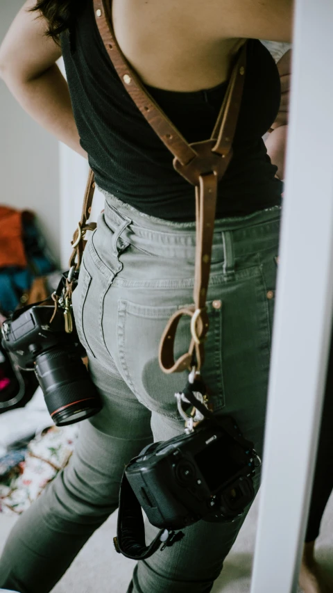 a girl holding two cameras in her arms and a bag