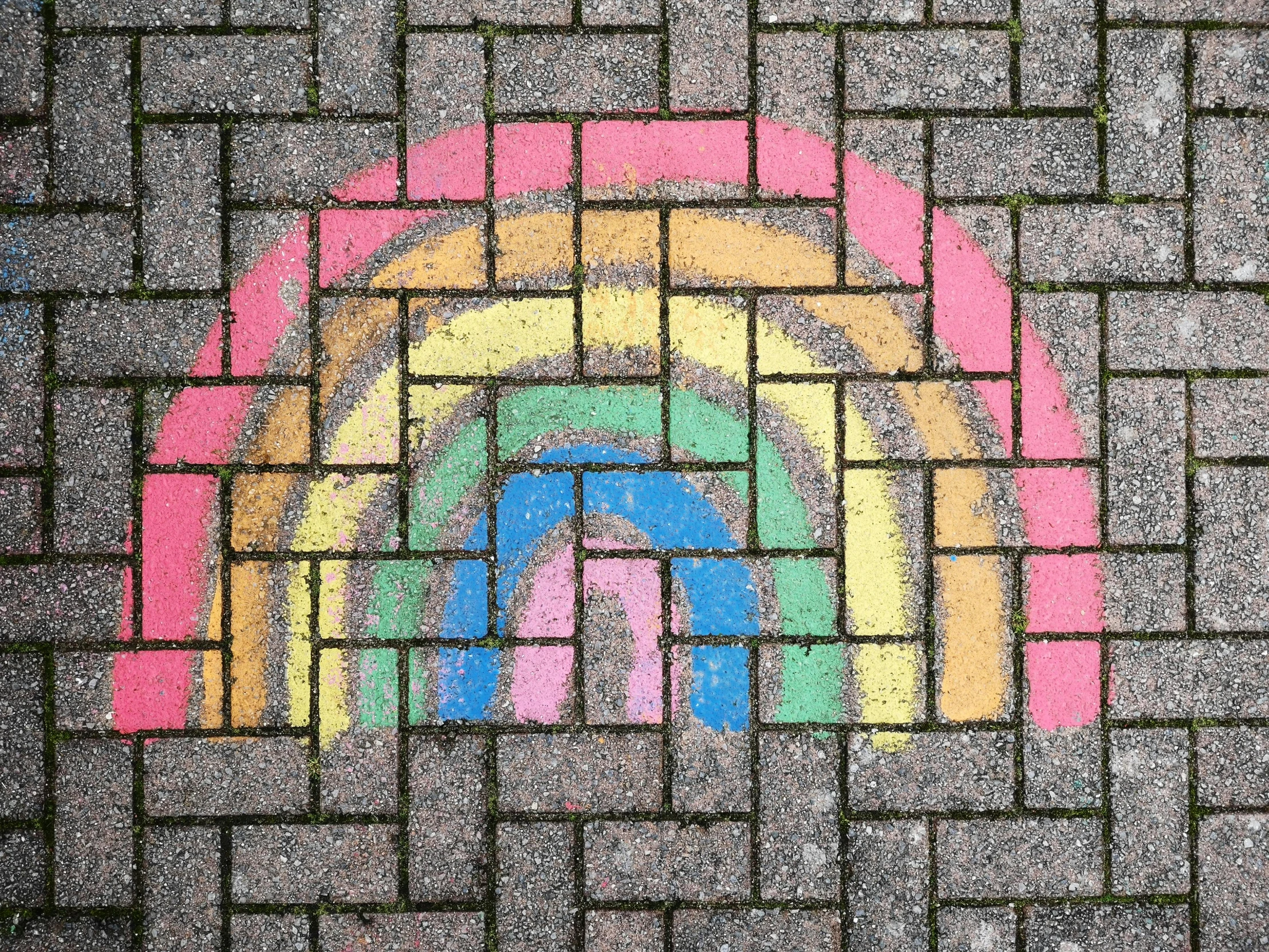 a colorful rainbow drawing is drawn on the sidewalk