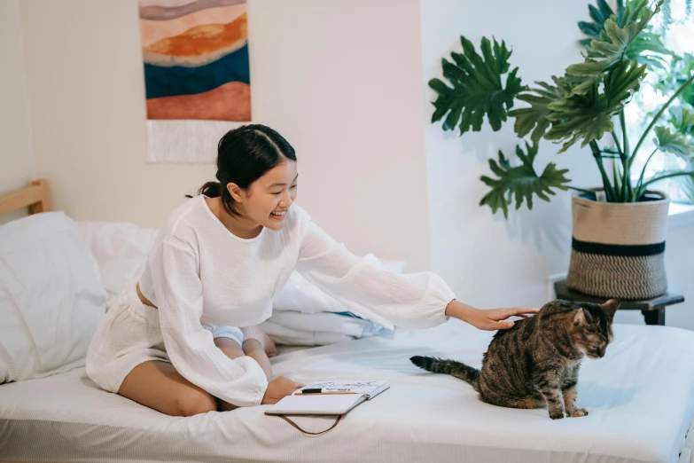 a woman is on a bed petting a cat