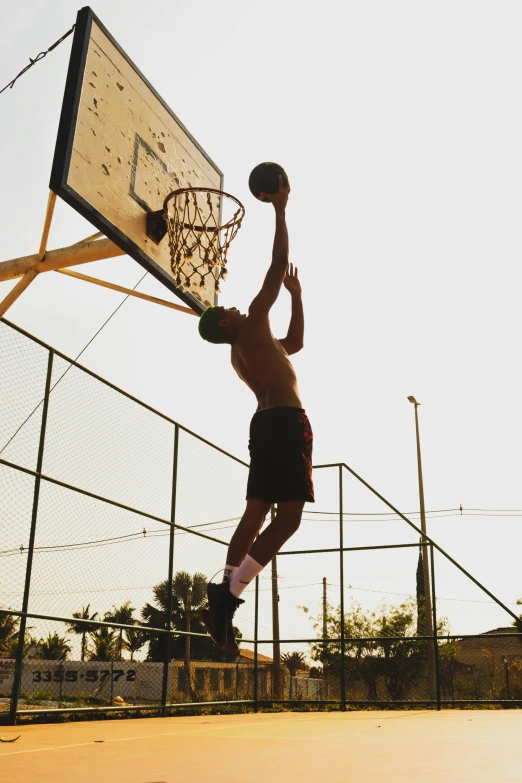 a shirtless man with  on playing basketball