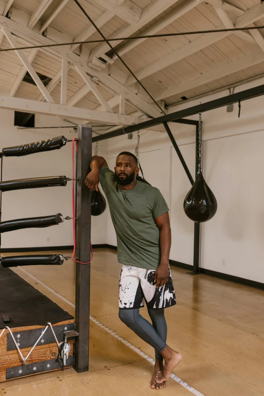 a man in a gym posing by a boxing bag