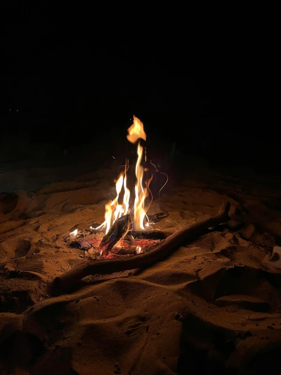 a bonfire on the beach is glowing bright