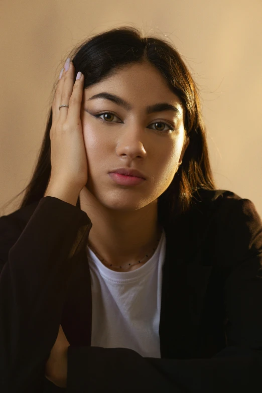 woman in black jacket with hand on head looking sideways