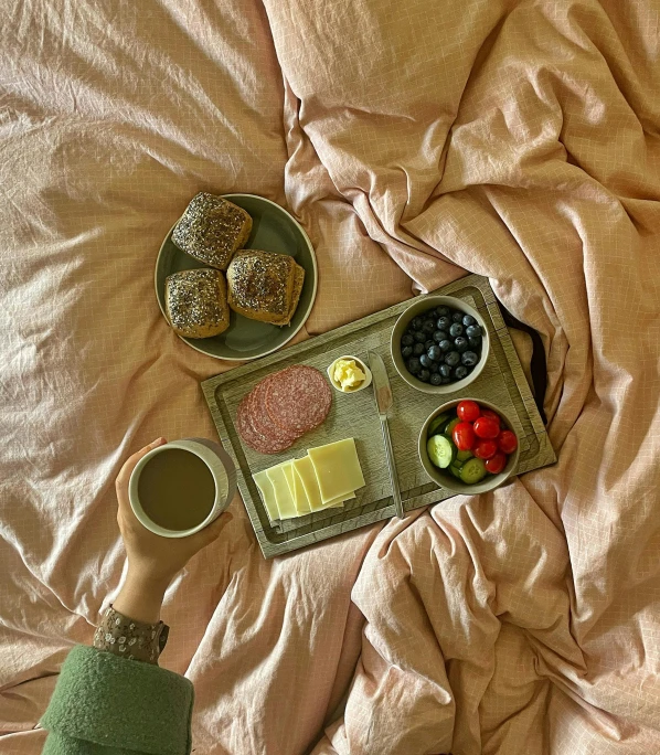 an open tray of cookies and fruit on a bed