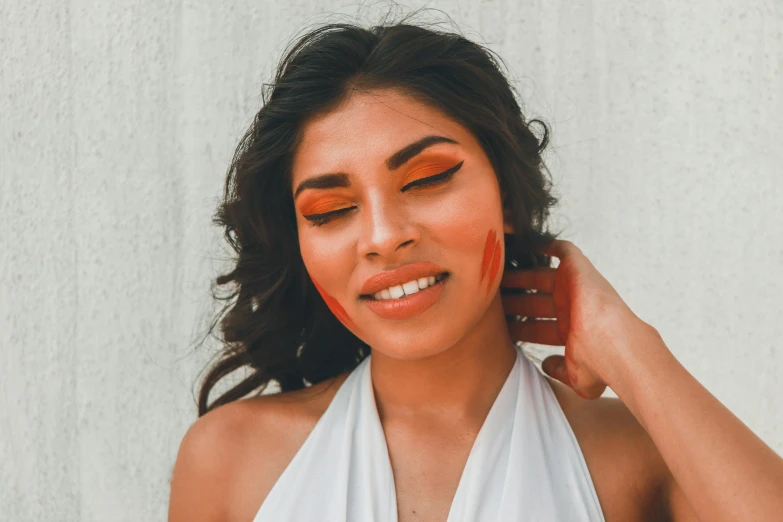 a woman standing in a dress with her eyes painted orange