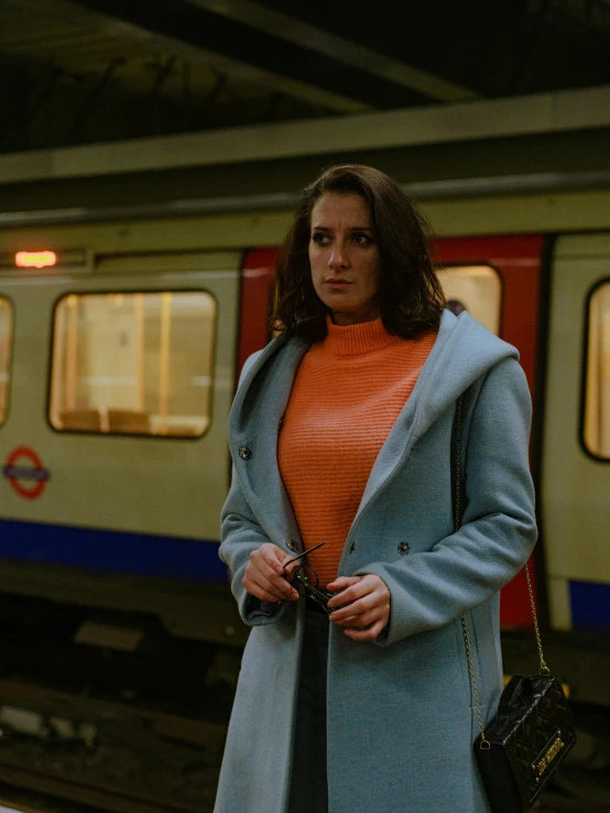 a woman with a handbag waiting for the subway