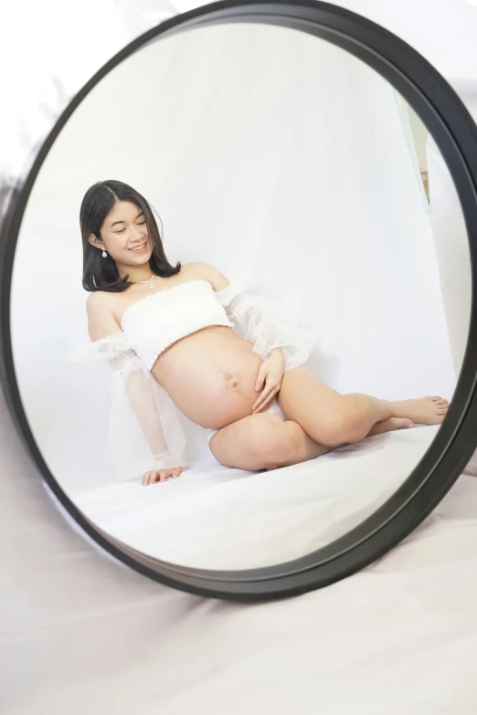 a pregnant woman in a white top is shown through a magnifying glass