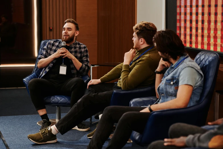 group of people sitting in chairs having a conversation