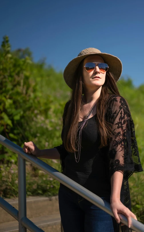 a woman wearing a hat and sunglasses walking down a staircase