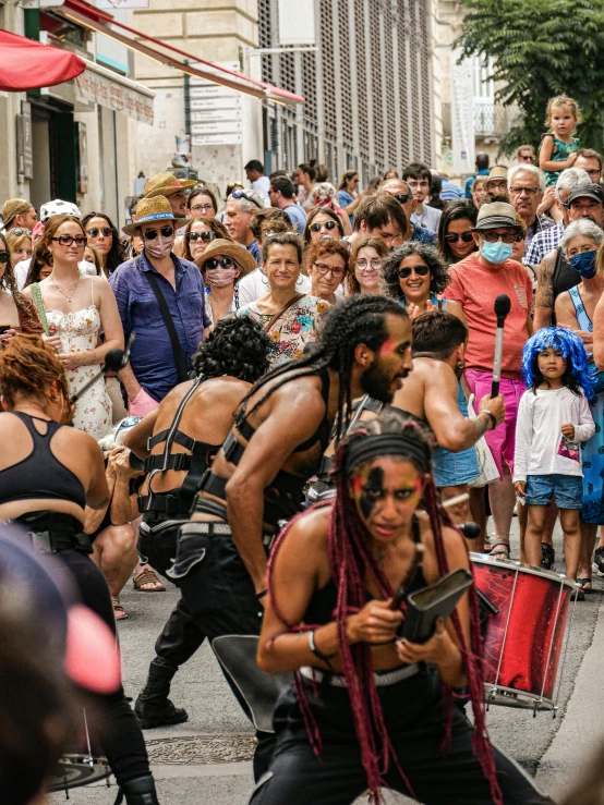 several men in body paint and with long dreadlocks on are performing a dance