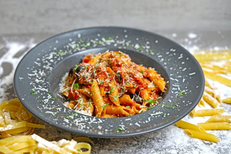 a plate with pasta, sauce and herbs in it