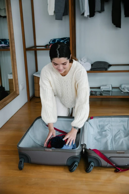 a woman opens her suitcase with a sweater on it