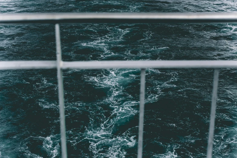 a boat traveling across a body of water next to a tall metal fence