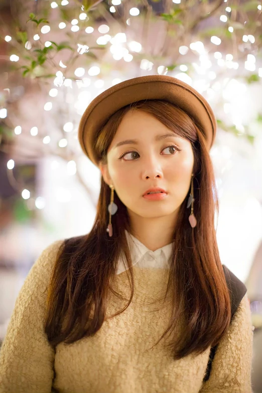 an asian girl with long hair wearing a tan sweater and pink earrings