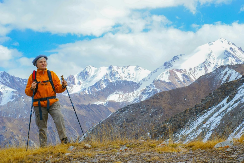 woman in orange jacket on mountains holding two ski poles