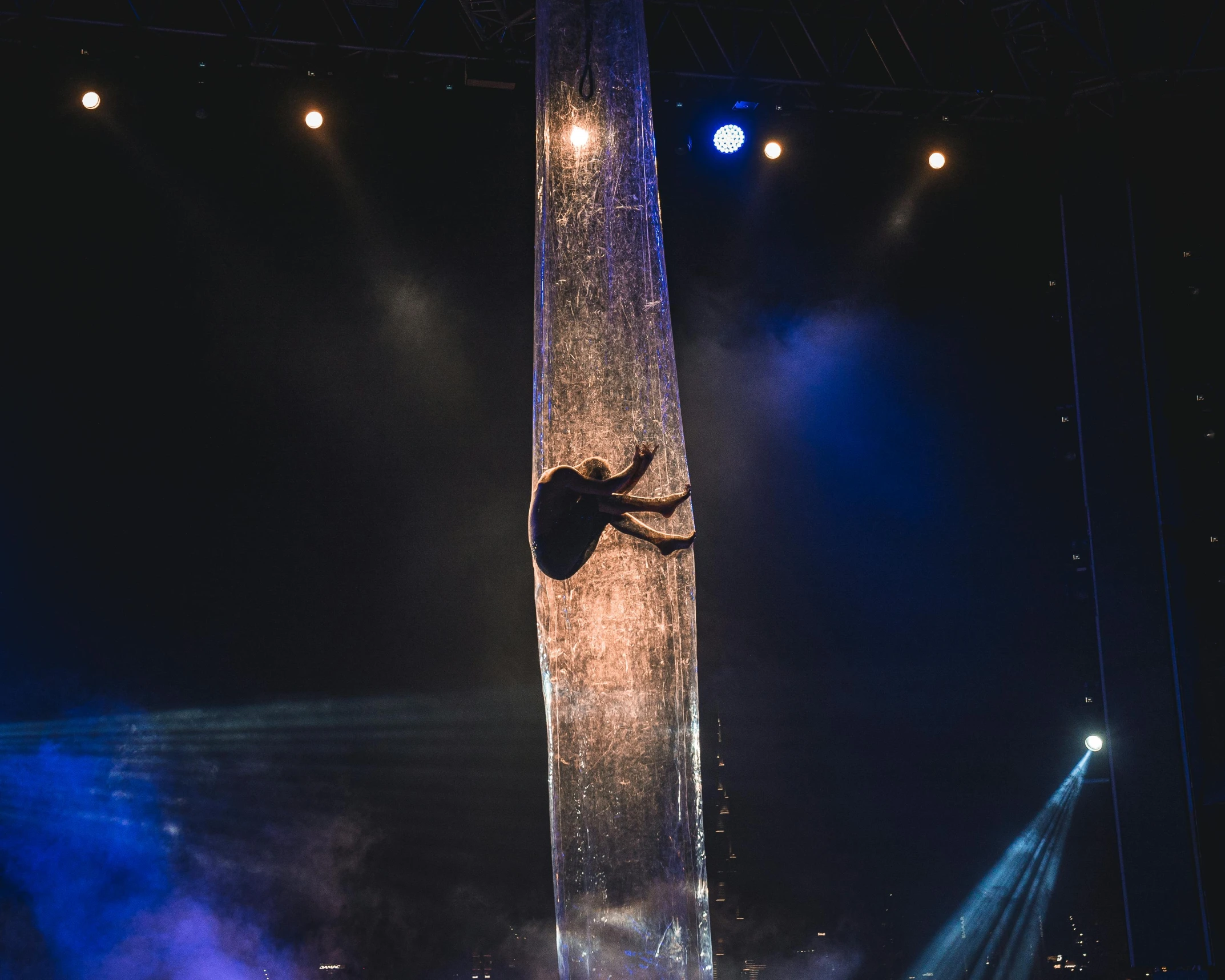 the acrobat stands on a pole and is surrounded by beams