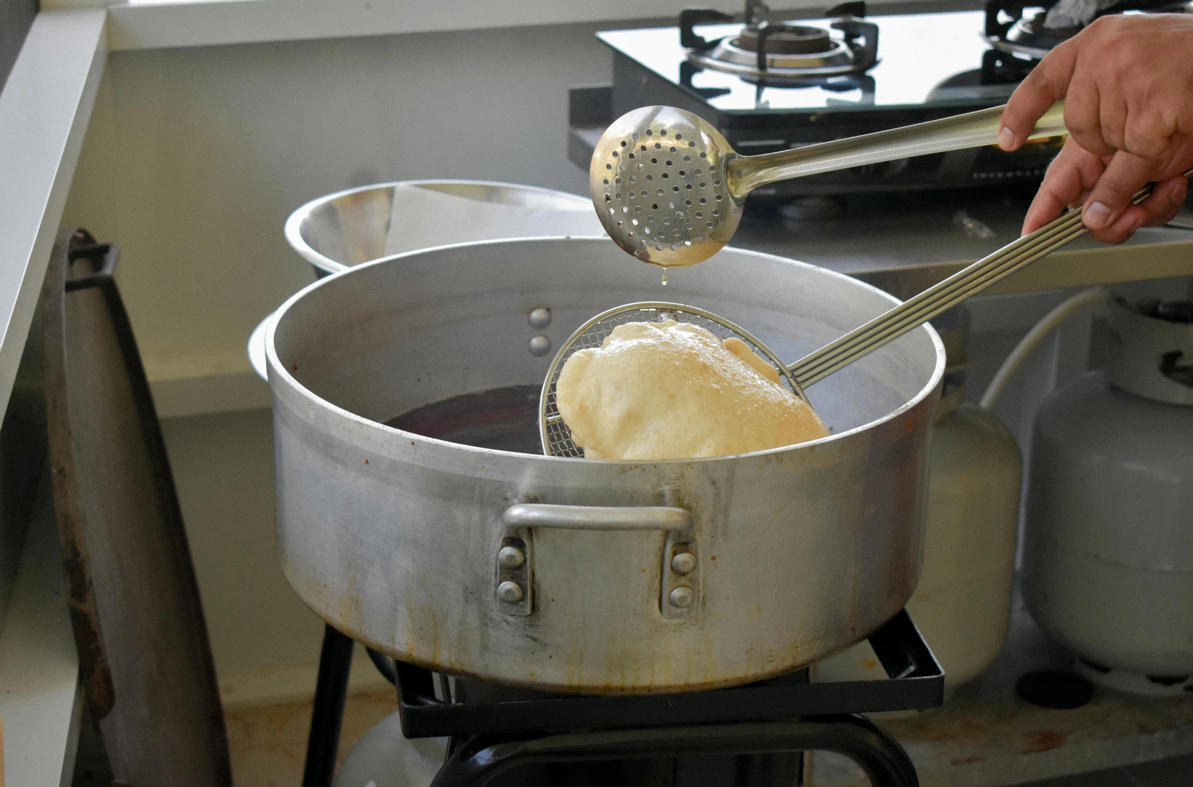 two pots and one holds a ladle as they sit on a stove