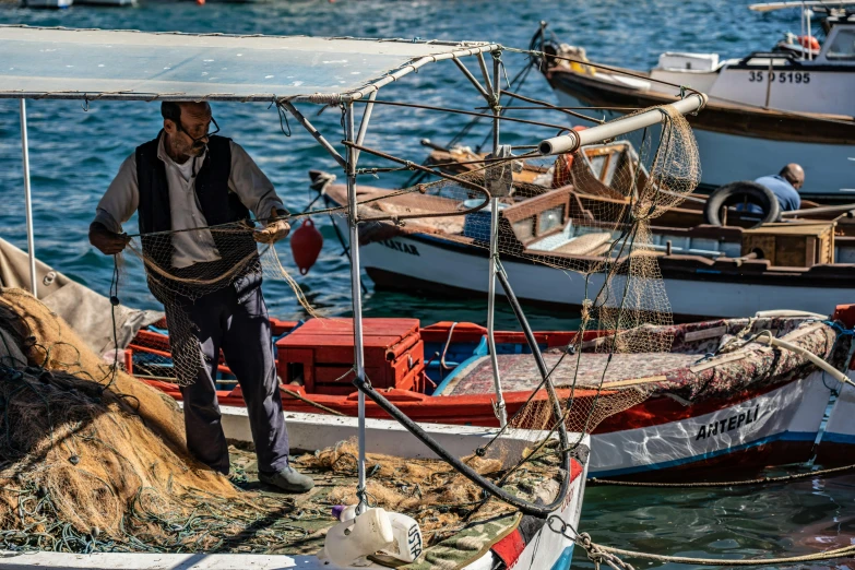 a man on the front of a fishing boat with nets