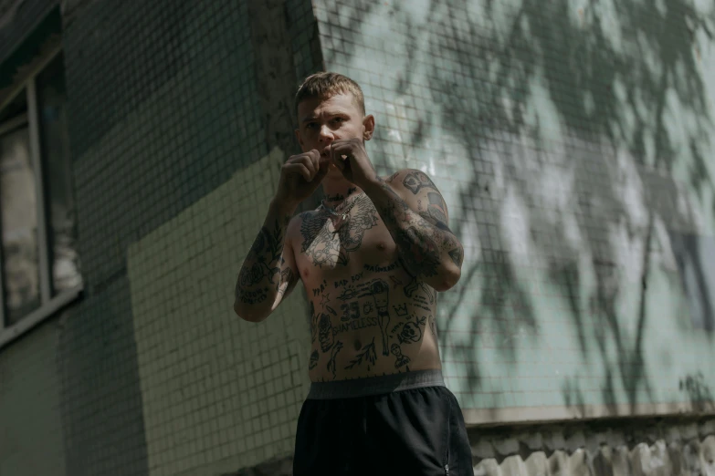 a man that is wearing lots of tattoos standing in front of a building