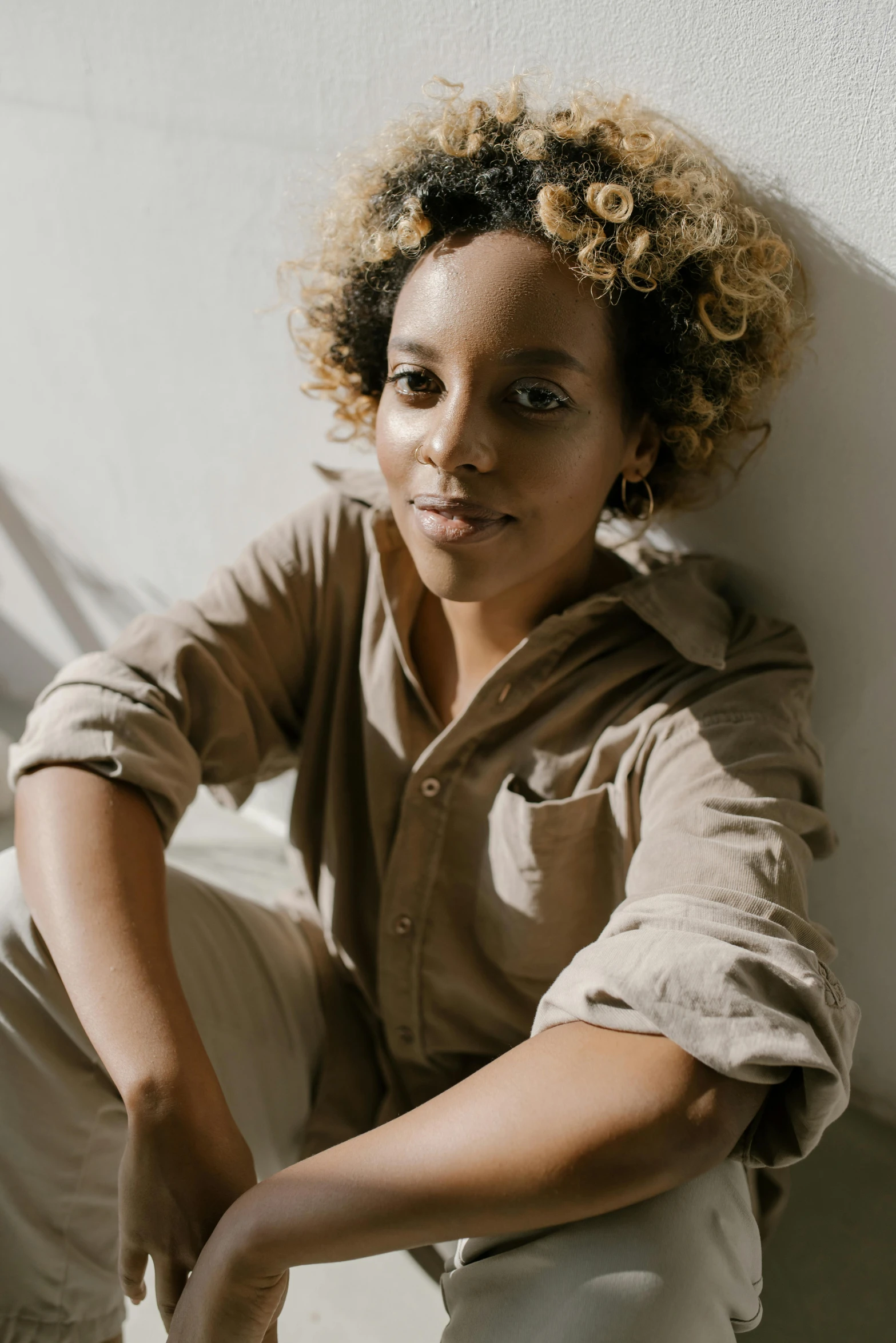 a smiling woman with a curly hair and some brown clothes