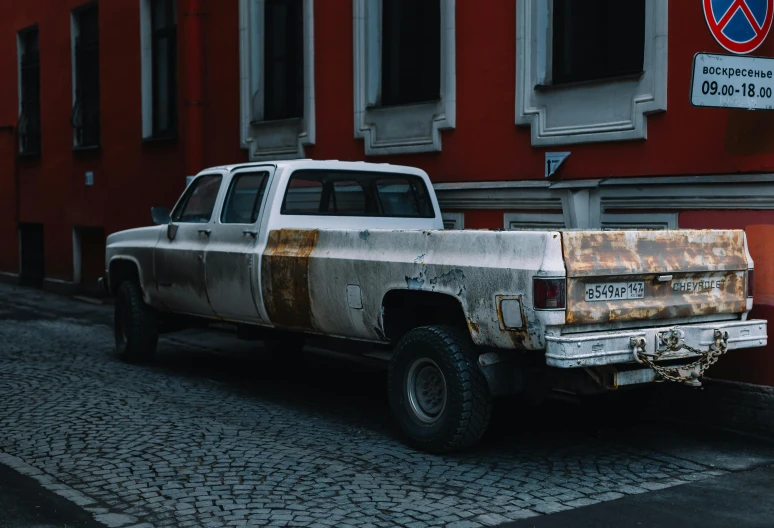 an old pickup truck that has rusted out parked on the side of a street