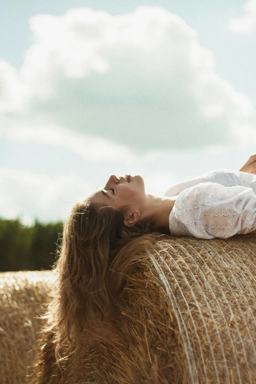 a woman lays on a bale of hay