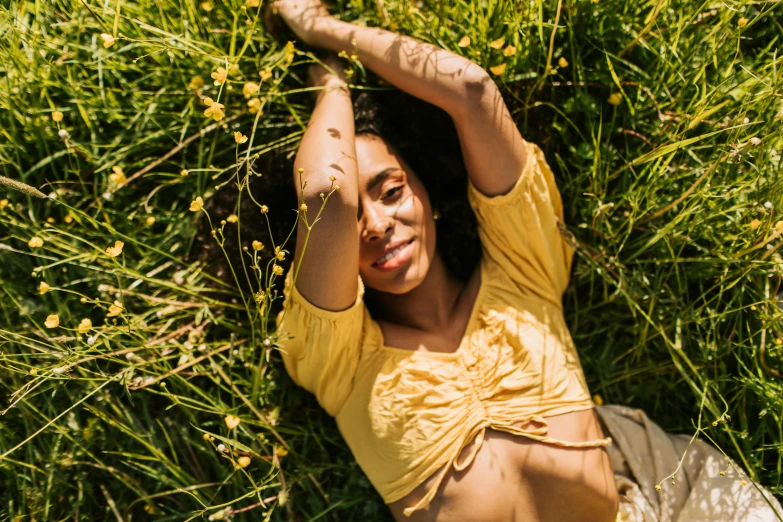 a woman in a yellow shirt lying down and looking up