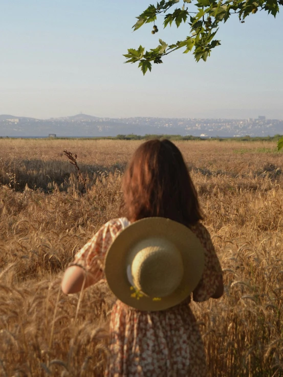 a woman standing in a field with a hat on