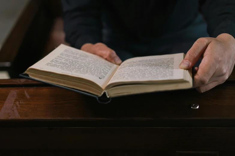 two hands holding open a book at a desk