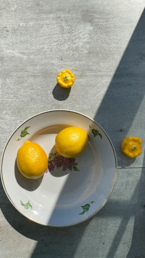 two yellow lemons placed on a white plate