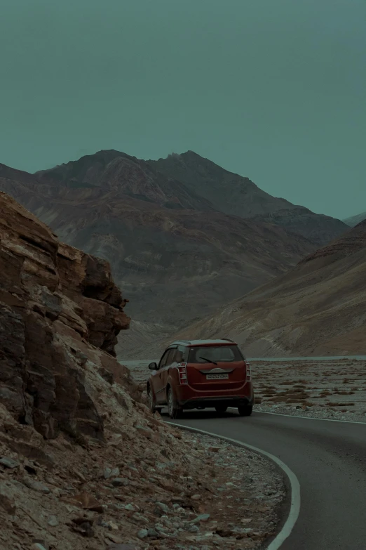 a red car driving down a winding mountain road