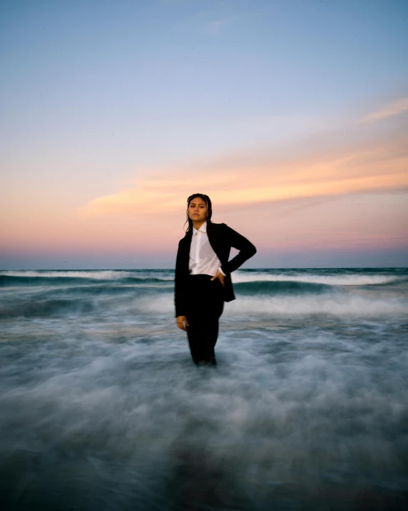 an asian woman standing in the ocean at sunset