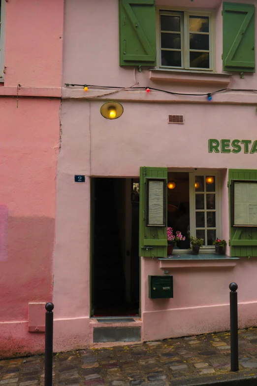 restaurant with green window boxes and doors and a pink building