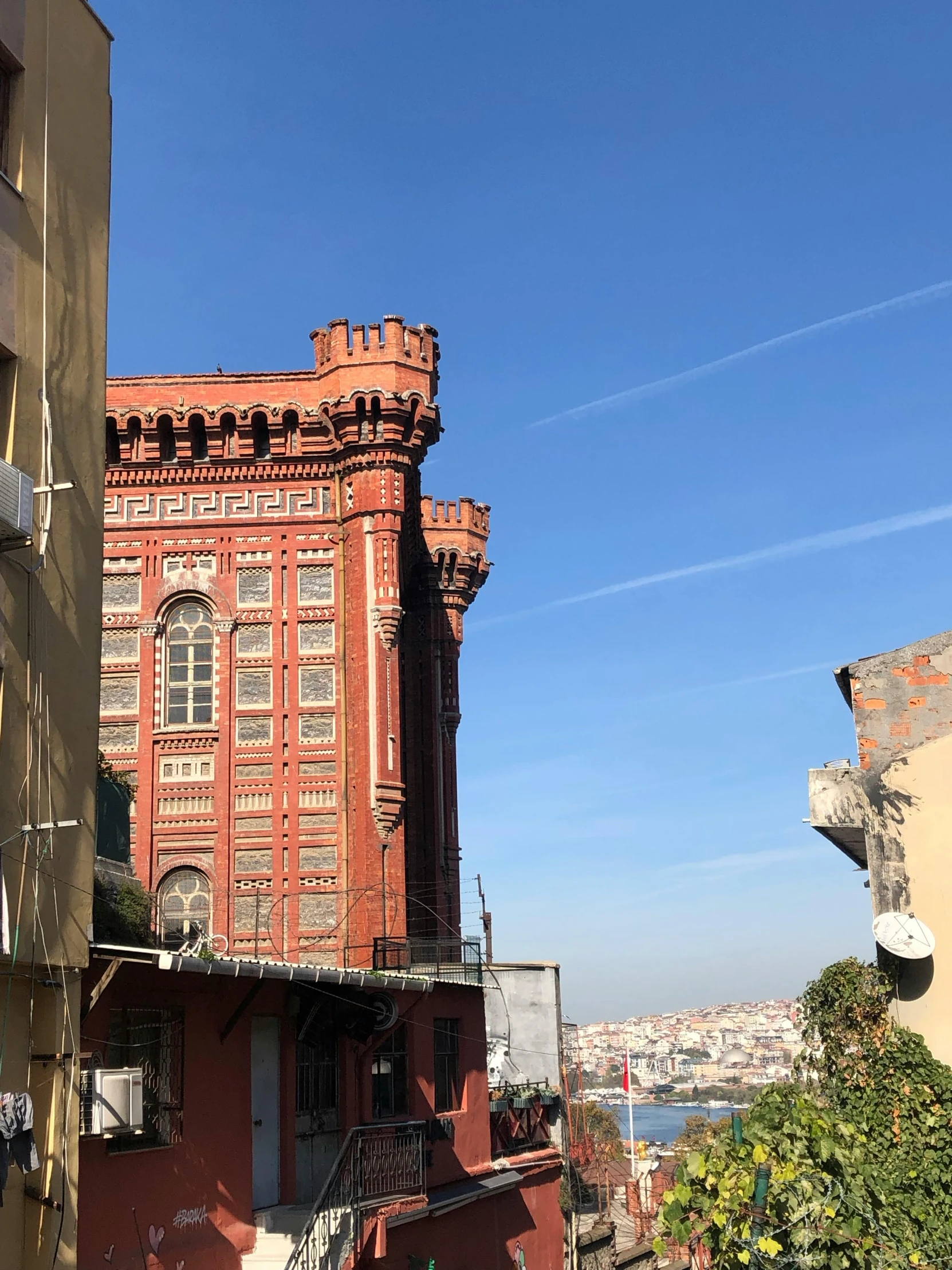 red brick building with balcony overlooking ocean and city