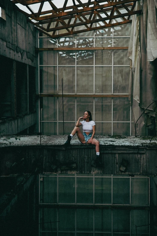 a woman sits on the edge of an abandoned building